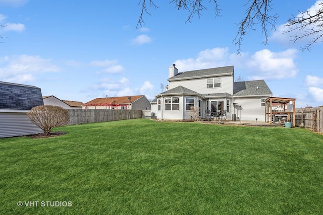 rear view of property featuring a fenced backyard, a chimney, roof with shingles, and a yard