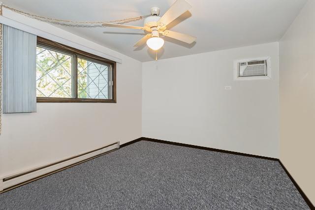 carpeted empty room featuring baseboards, baseboard heating, ceiling fan, and a wall unit AC