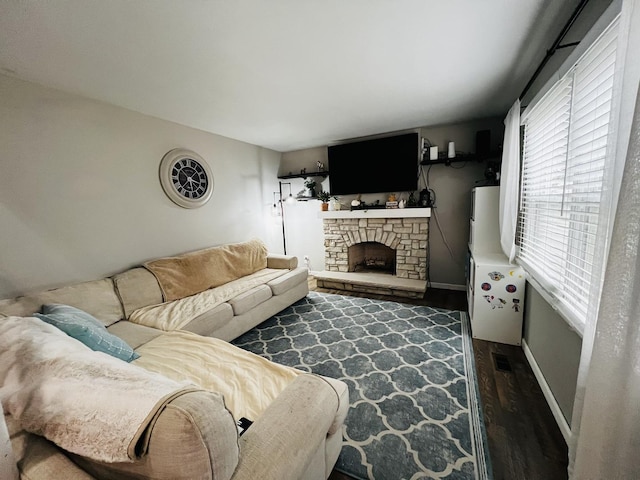 living area featuring visible vents, baseboards, a fireplace, and dark wood-style flooring