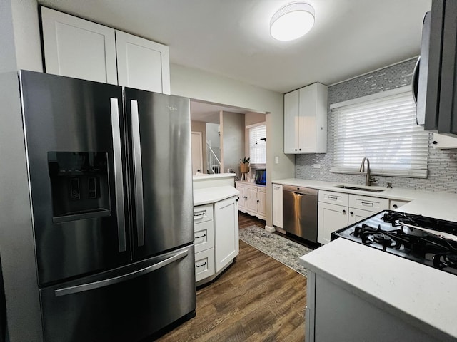 kitchen with dark wood finished floors, appliances with stainless steel finishes, tasteful backsplash, and a sink