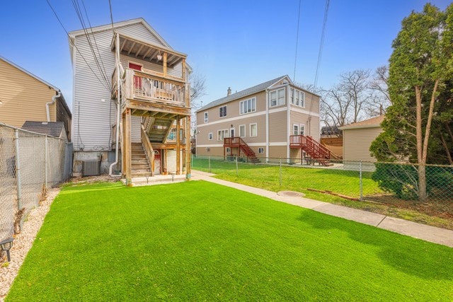 rear view of property with a fenced backyard, stairway, cooling unit, and a lawn