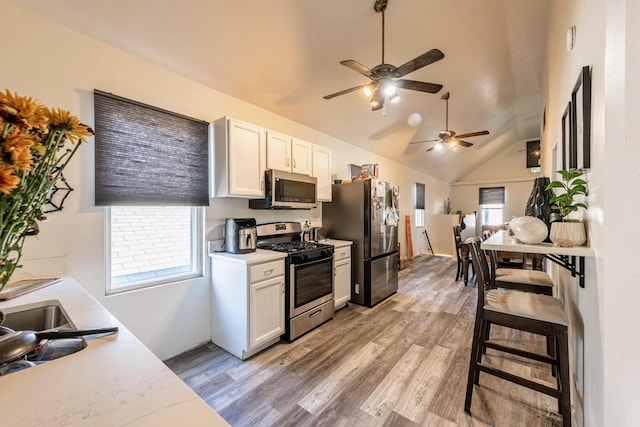 kitchen featuring light wood finished floors, stainless steel appliances, white cabinets, a ceiling fan, and light countertops