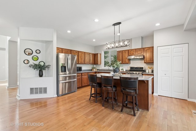 1635 Arlington Ln, Gurnee, IL 60031 - kitchen featuring stainless steel appliances, under cabinet range hood, a center island, light wood-style flooring, and a kitchen breakfast bar
