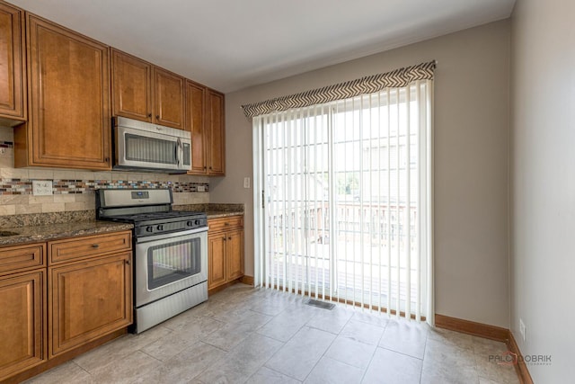 1680 Bicek Dr, Hoffman Estates, IL 60192 - kitchen featuring appliances with stainless steel finishes, decorative backsplash, brown cabinets, and dark stone counters