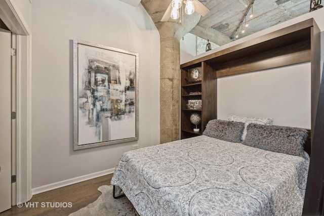 bedroom featuring wood finished floors, rail lighting, and baseboards