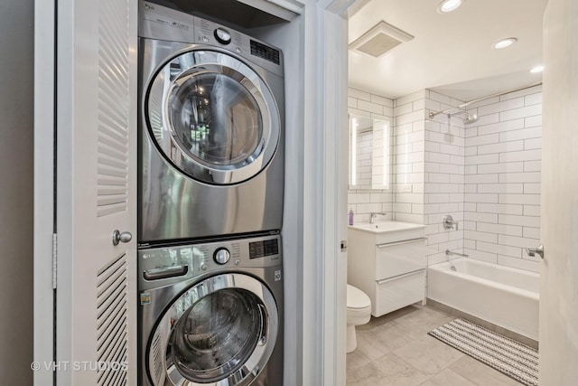 bathroom with shower / bathing tub combination, vanity, toilet, stacked washer and clothes dryer, and visible vents