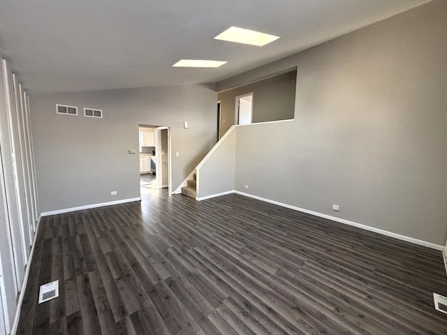 spare room featuring stairway, lofted ceiling, dark wood-type flooring, and visible vents