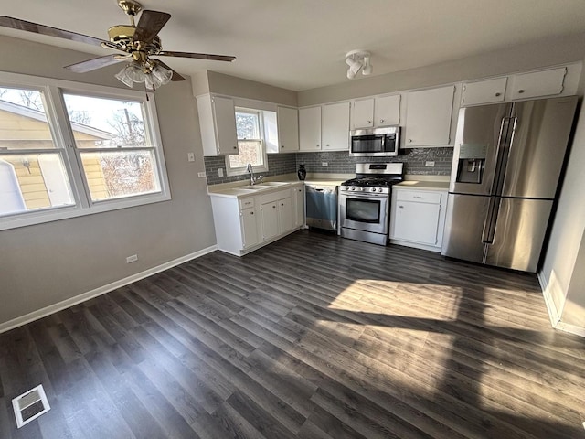 kitchen featuring stainless steel appliances, light countertops, a sink, baseboards, and decorative backsplash