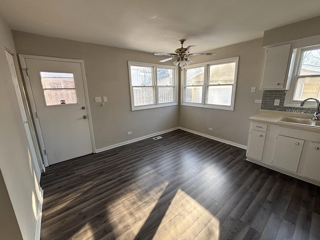 interior space with light countertops, a ceiling fan, a sink, a wealth of natural light, and dark wood-style flooring