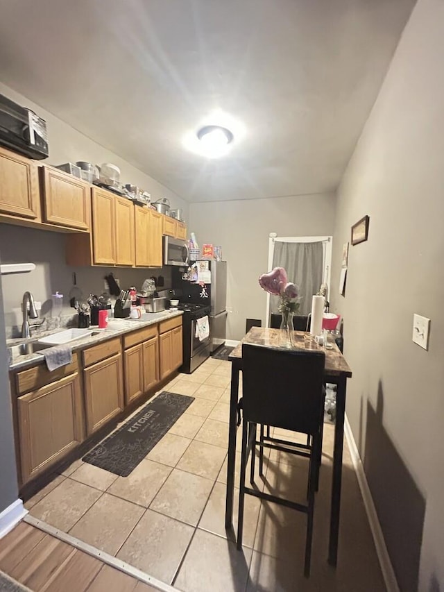 7038 S Vernon Ave, Chicago, IL 60637 - kitchen featuring a sink, stainless steel microwave, black gas range, light countertops, and light tile patterned floors