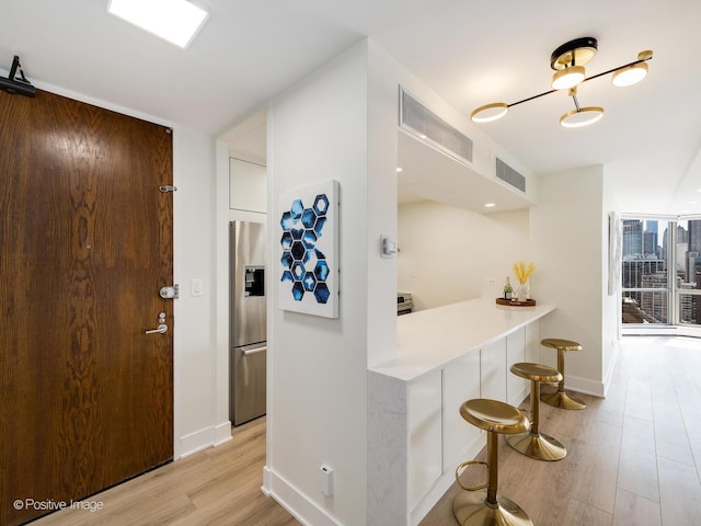 1310 N Ritchie Ct Unit 27B, Chicago, IL 60610 - kitchen with stainless steel fridge, light wood-style flooring, a kitchen bar, baseboards, and light countertops