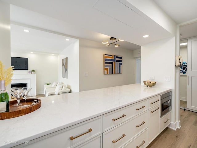 1310 N Ritchie Ct Unit 27B, Chicago, IL 60610 - kitchen featuring stainless steel microwave, light stone counters, light wood-style flooring, white cabinets, and recessed lighting