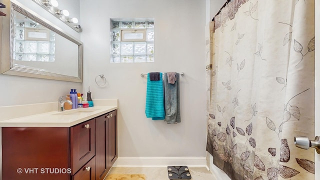 bathroom featuring vanity, baseboards, and curtained shower