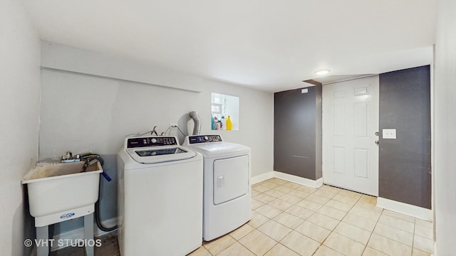 washroom with separate washer and dryer, light tile patterned flooring, and baseboards