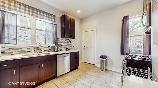 kitchen featuring a sink, stainless steel appliances, light countertops, decorative backsplash, and baseboards
