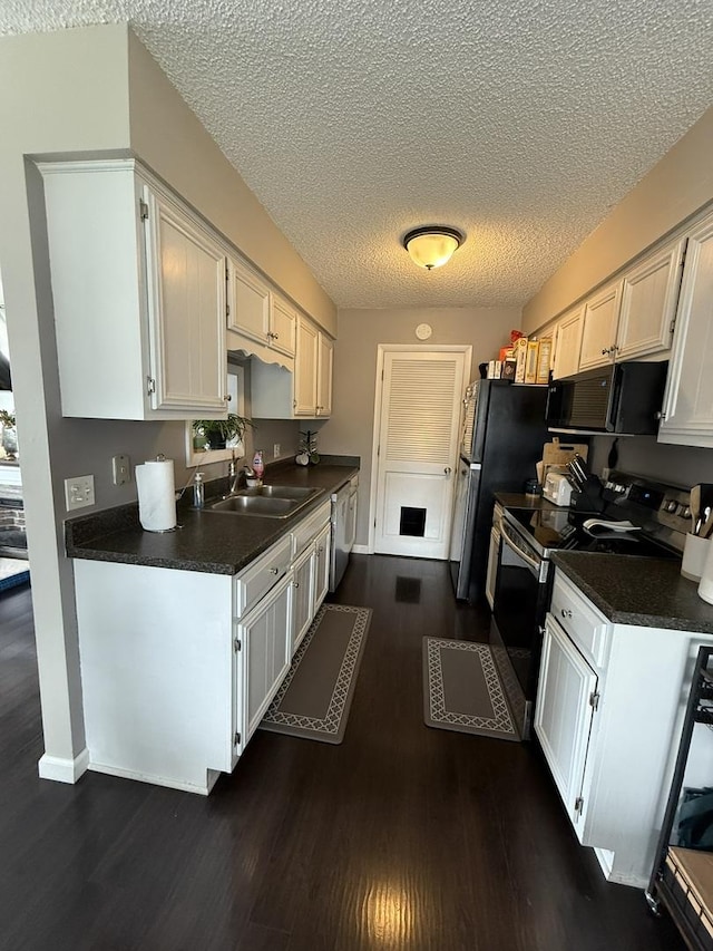 kitchen featuring a sink, stainless steel range with electric stovetop, dishwasher, and dark countertops