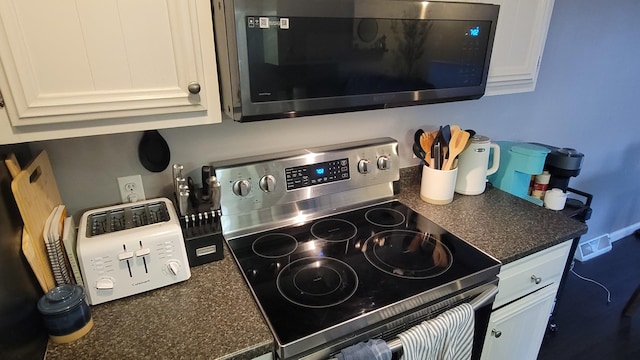 kitchen featuring stainless steel electric range oven and white cabinetry
