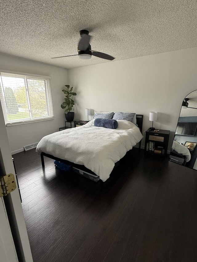 bedroom featuring baseboards, a ceiling fan, a textured ceiling, and wood finished floors