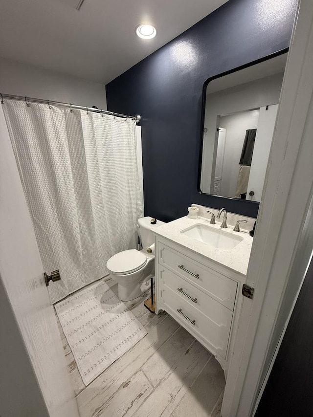 bathroom with vanity, toilet, a shower with shower curtain, recessed lighting, and wood finished floors