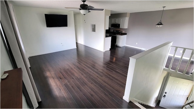 unfurnished living room with a ceiling fan, baseboards, and dark wood-type flooring