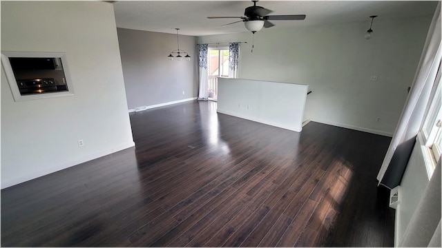 empty room featuring ceiling fan, dark wood-style flooring, and baseboards