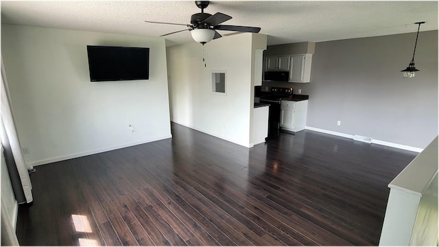 unfurnished living room featuring a textured ceiling, visible vents, dark wood finished floors, ceiling fan, and baseboards