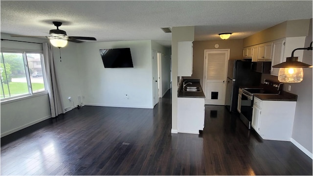 kitchen featuring a sink, dark countertops, electric range, a textured ceiling, and visible vents