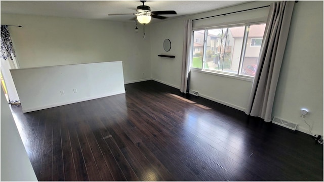 spare room featuring a ceiling fan, baseboards, dark wood-style floors, and visible vents
