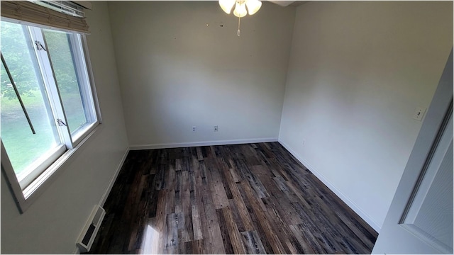spare room with baseboards, dark wood-style floors, a ceiling fan, and visible vents