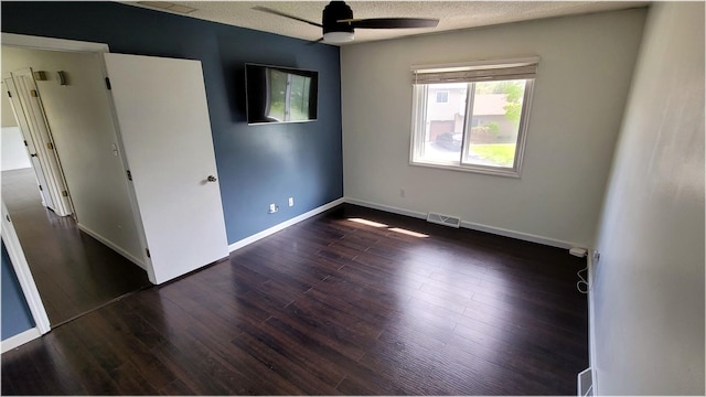 unfurnished bedroom with a ceiling fan, a textured ceiling, visible vents, dark wood-style flooring, and baseboards