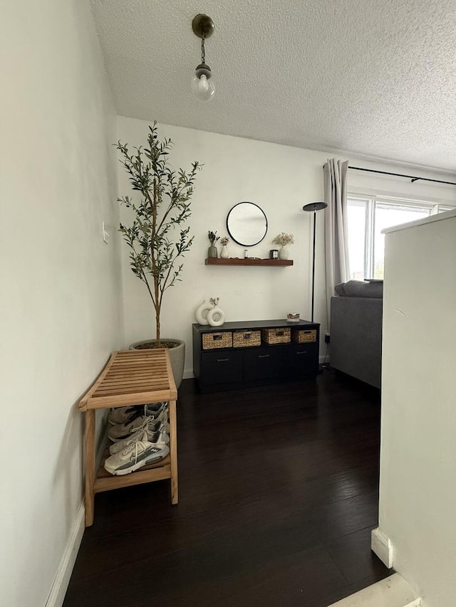 hall with baseboards, a textured ceiling, and dark wood-style flooring
