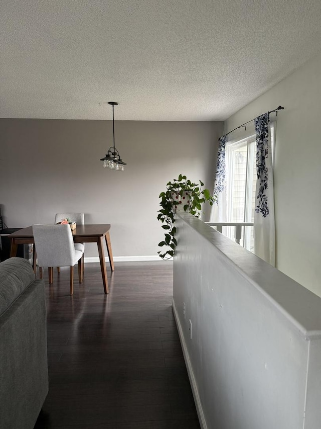 corridor with dark wood-type flooring, a textured ceiling, and baseboards