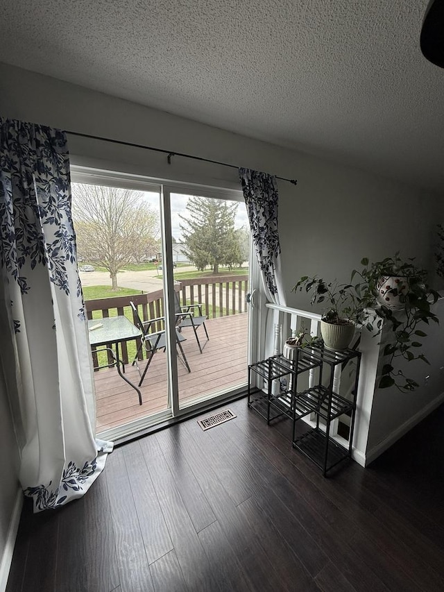 interior space with visible vents, a textured ceiling, dark wood-style flooring, and a healthy amount of sunlight