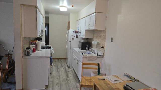 kitchen featuring light wood-type flooring, light countertops, white cabinets, and freestanding refrigerator