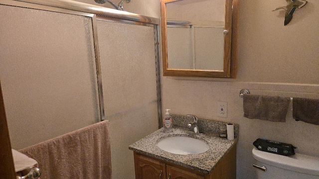 bathroom featuring vanity, a shower with shower door, and toilet