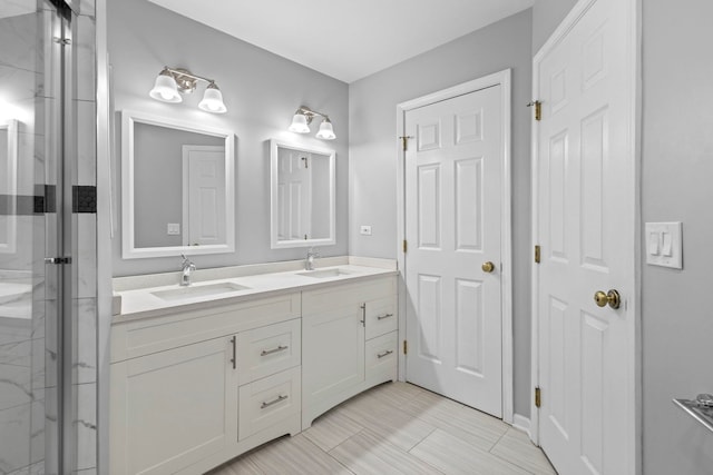 bathroom featuring a marble finish shower, a sink, and double vanity