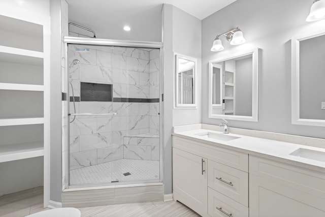 bathroom featuring a marble finish shower, a sink, and double vanity
