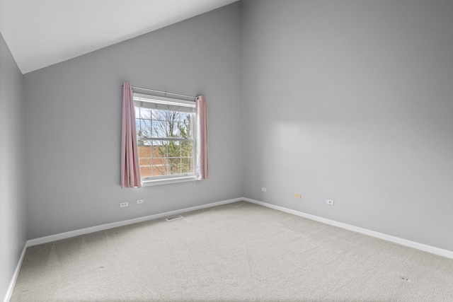 carpeted spare room featuring lofted ceiling, baseboards, and visible vents