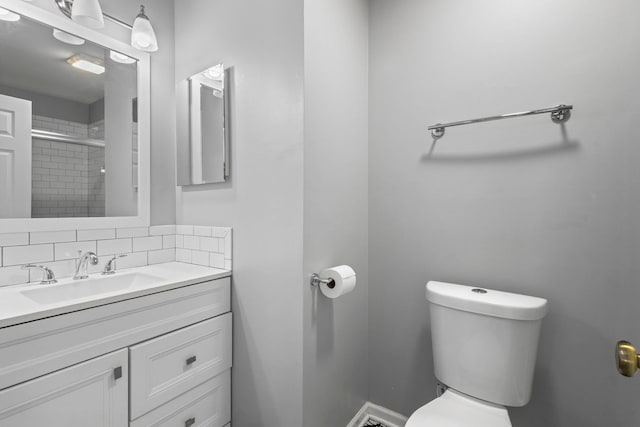full bathroom with a tile shower, vanity, and toilet