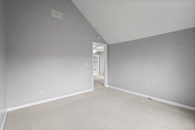 carpeted spare room featuring lofted ceiling, visible vents, and baseboards