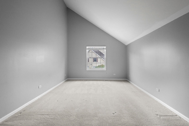 empty room with carpet floors, vaulted ceiling, and baseboards