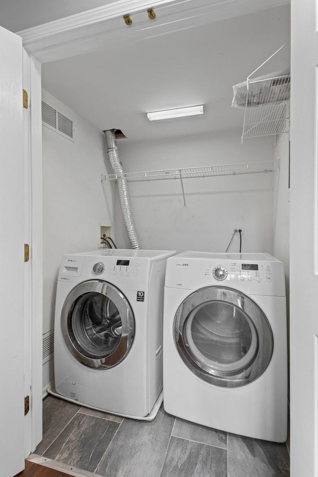 washroom with laundry area, wood finished floors, washer and clothes dryer, and visible vents