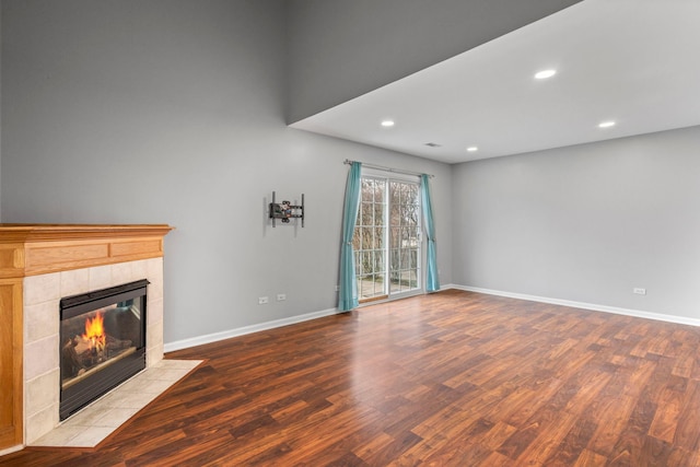 unfurnished living room featuring baseboards, a tile fireplace, wood finished floors, and recessed lighting