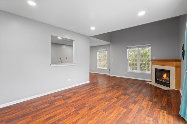 unfurnished living room with a tile fireplace, baseboards, wood finished floors, and recessed lighting