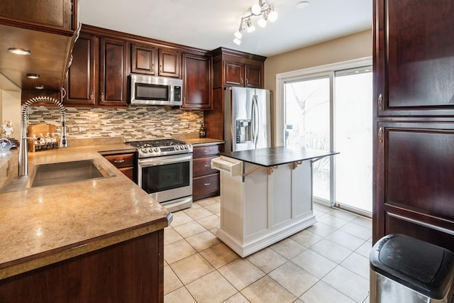 kitchen featuring stainless steel appliances, a sink, dark brown cabinetry, backsplash, and light tile patterned floors