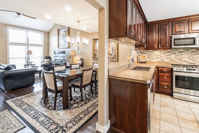 kitchen with tasteful backsplash, a sink, open floor plan, light countertops, and appliances with stainless steel finishes