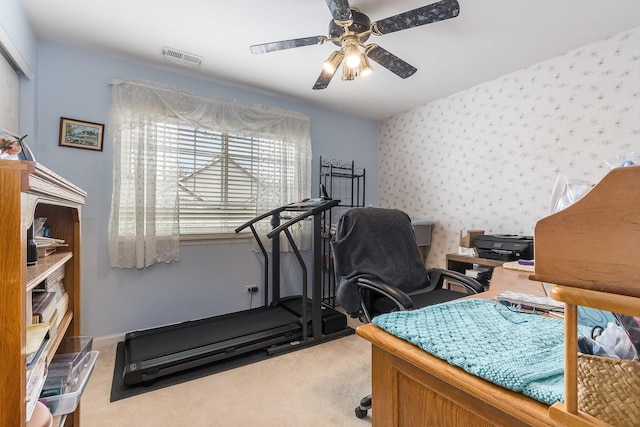 carpeted office space with wallpapered walls, visible vents, and ceiling fan