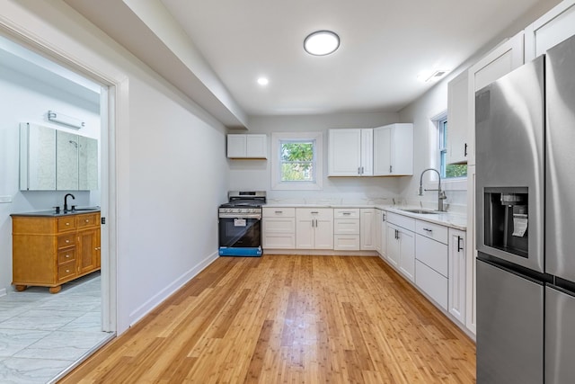 kitchen featuring white cabinets, visible vents, a sink, light wood-type flooring, and appliances with stainless steel finishes