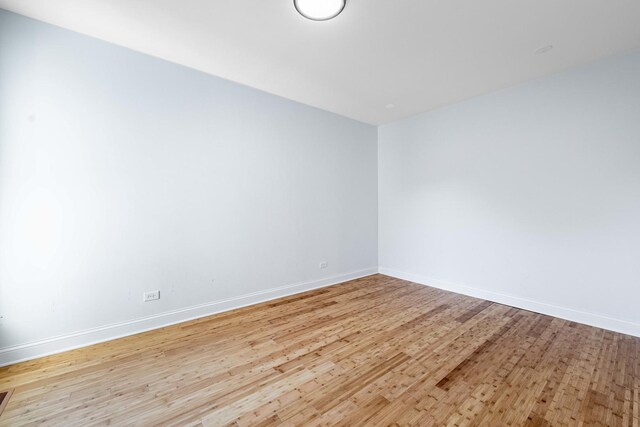 unfurnished room featuring wood finished floors, visible vents, and baseboards