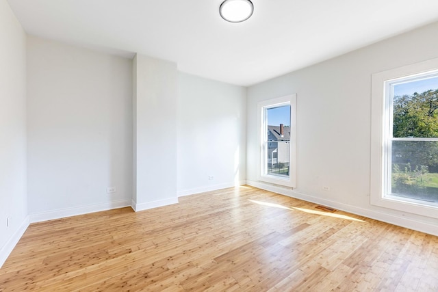 spare room featuring light wood-style flooring, a wealth of natural light, and baseboards